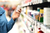 Customer in pharmacy holding medicine bottle. 