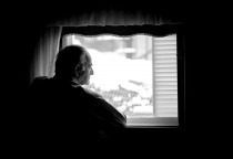 Lonely senior man looking at the window